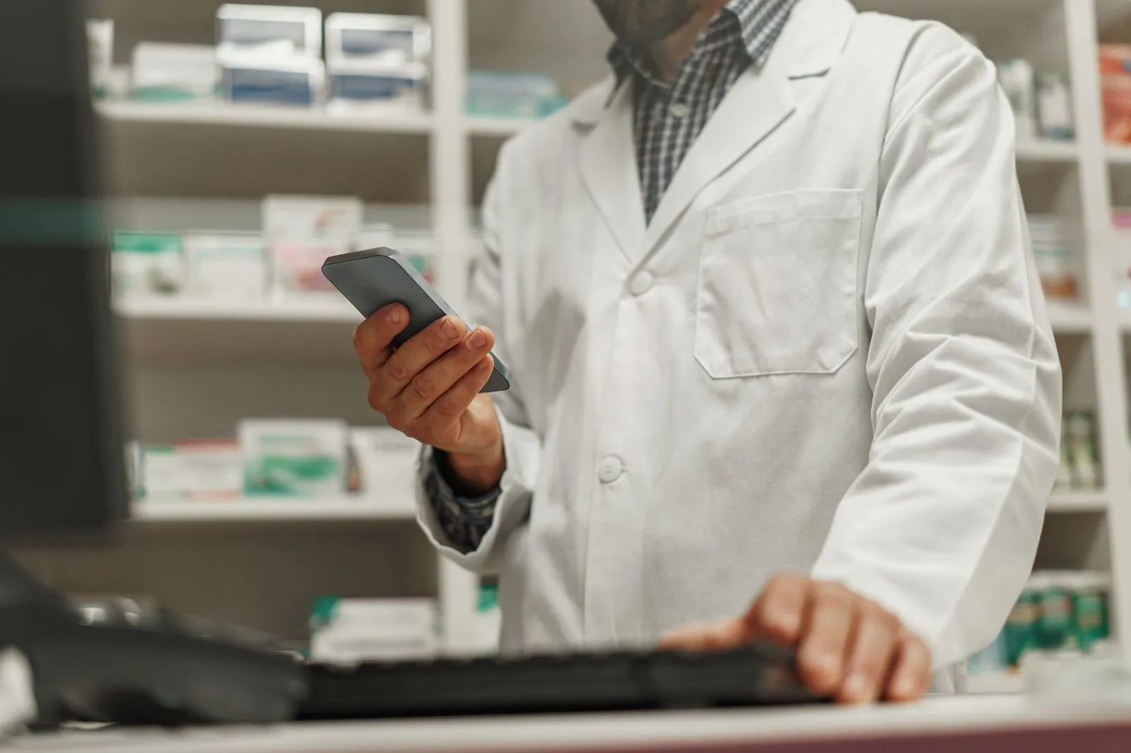 Un farmacista al banco controlla i suoi obiettivi sul telefono