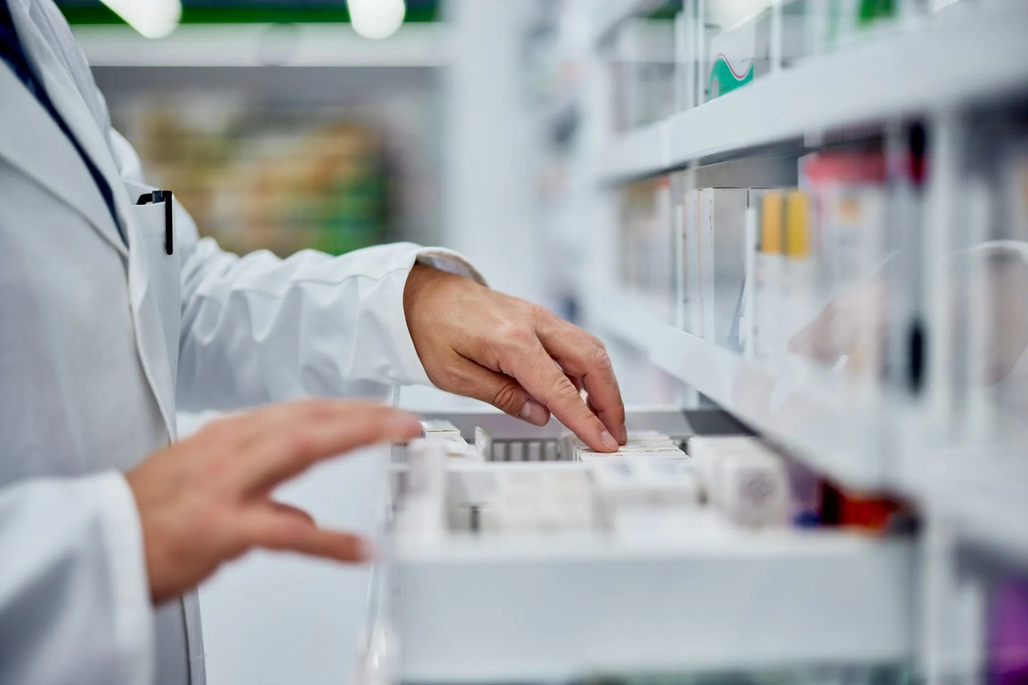 Una farmacista prende una confezione da un cassetto della farmacia