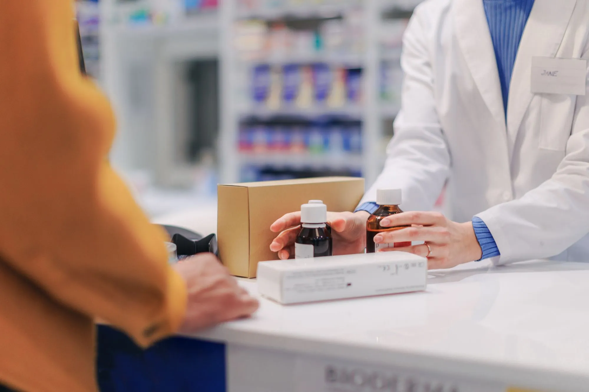 Al banco della farmacia una farmacista mostra due flaconi a una cliente